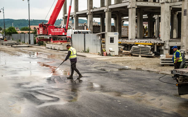 Sibiu, Romania - June 05, 2019, Worker washes the dirty pavement with water in front of the mall Festival Centrum building site from Sibiu city, Romania
